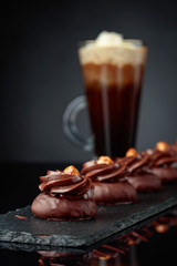 Chocolate dessert with hazelnut and coffee with cream on a black background.