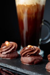  Chocolate dessert with hazelnut and coffee with cream on a black background.
