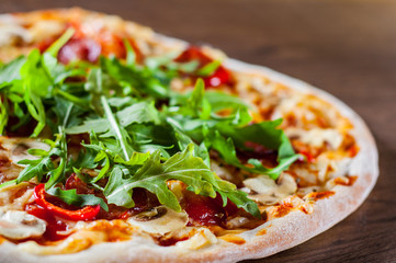 Pizza with Mozzarella cheese, mushrooms, pepperoni, tomato sauce, salami, pepper, Spices and Fresh arugula. Italian pizza on wooden table background