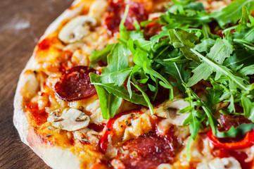 Pizza with Mozzarella cheese, mushrooms, pepperoni, tomato sauce, salami, pepper, Spices and Fresh arugula. Italian pizza on wooden table background