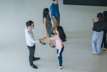 Asian office workers shake hands to greet each other in the office lobby