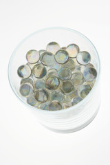 LIGHT SHINING THROUGH GLASS TUMBLER FILLED WITH TRANSPARENT COLOURED GLASS BALLS