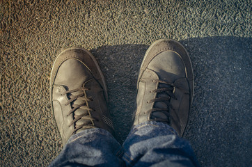 men's legs in black shoes on gray asphalt