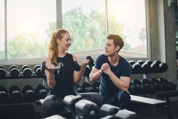 Beautiful woman is exercising and fitness. The trainer gives instructions on how to exercise in the gym.