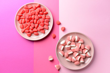 Plates with tasty sweet candies on color background