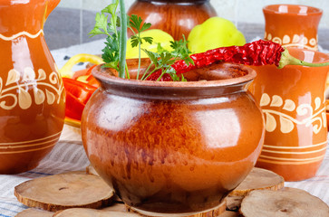 Traditional rustic home  gulyas, with raw vegetables and spices in clay pots on  wooden table.