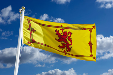 SCOTTISH YELLOW AND RED NATIONAL FLAG WITH BLUE SKY AND WHITE CLOUDS