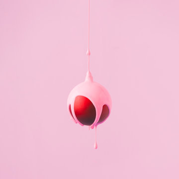 Red Christmas bauble decoration with pastel pink paint dripping. Minimal New Year concept.