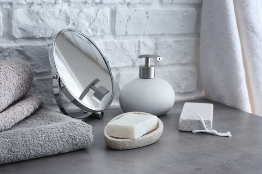 Soap with towels and mirror on grey table in bathroom