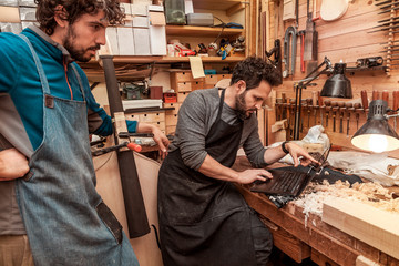 two craftsmen violinmakers checking a new violin - obrazy, fototapety, plakaty