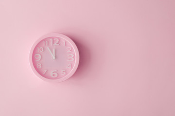 Pastel pink clock on pink painted wall. Minimal time concept. Chrismas eve or new year idea.