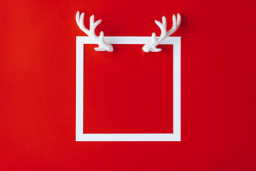 Reindeer antlers with white frame on red background. Christmas minimal copy space. Greeting card.