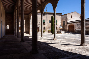 Spain, Catalonia, Castello d'Empuries: Detail view of public square arcades near Basílica de Santa Maria in the city center of the famous old medieval Spanish town - concept travel history plaza