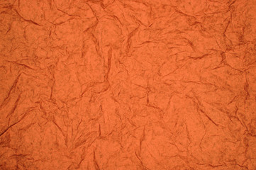 ABSTRACT RANDOM BACKGROUND OF CREASED CRUMPLED ORANGE RED TISSUE PAPER