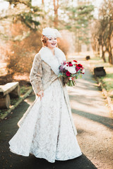 Fototapeta na wymiar Beautiful luxury young bride in wedding dress posing in park