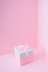 Close view minimal composition of pink Christmas gift box on pastel backdrop. New Year present concept background.