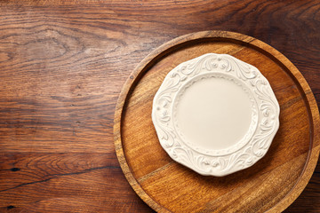 Empty white blank plate on wooden background with copy space. Top view.