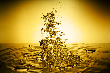 Yellow oil splashing into water background 
