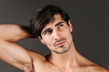 Handsome thoughtful serious young smiling man posing isolated over dark wall background.