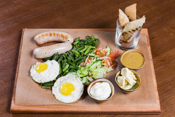 Omelette with sausages and vegetables on wooden table. Tasty food in the restaurant. Gourmet. English breakfast