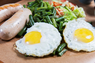 Omelette with sausages and vegetables on wooden table. Tasty food in the restaurant. Gourmet. English breakfast