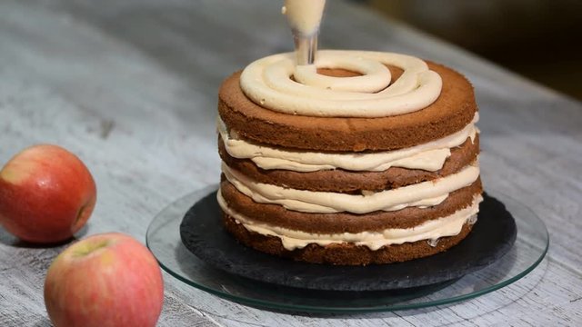 A chef decorates a cake with a cream.