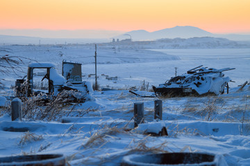 Old broken truck and all-terrain vehicle in a car dump in the tundra among the snow. Environmental pollution, landfills, and garbage in nature. Chukotka, Siberia, the Far East of Russia.