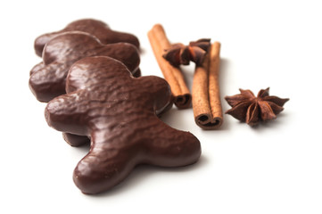 closeup of christmas gingerbread chocolate coated biscuit in shaped man with anise flower and cinnamon stick on white background