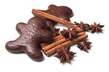 closeup of christmas gingerbread chocolate coated biscuit in shaped man with anise flower and cinnamon stick on white background