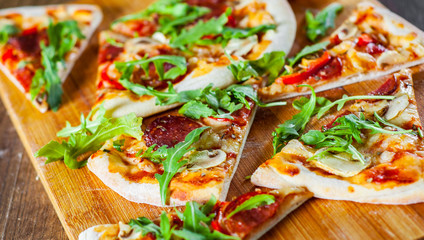 slices Pizza with Mozzarella cheese, mushrooms, pepperoni, tomato sauce, salami, pepper, Spices and Fresh arugula. Italian pizza on wooden table background