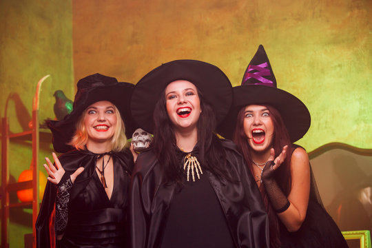 Portrait of screaming three young witches in black hats