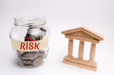 A glass jar and the inscription Risk stands next to a state building. The concept of financial and economic risk. Unreliable investment. Unpaid loan. Financial risk management. Commercial loan
