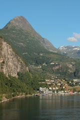 Settlement on sea coast at foot of mountains. Geiranger, Norway