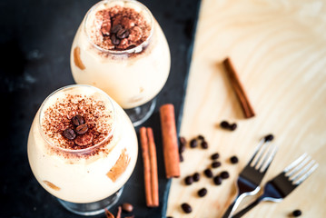 tiramisu in a glass decorated with coffee beans on a dark background
