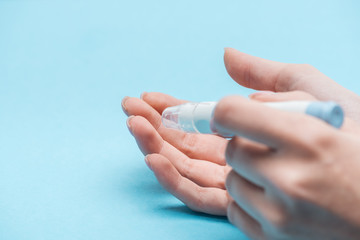 cropped view of female hands testing glucose level with needle on blue background