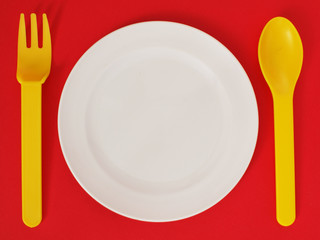 empty plate with fork and knife on red background