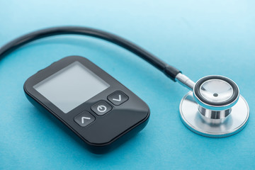 Fototapeta na wymiar close up view of glucometer and stethoscope on blue background