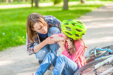 Little girl shows mother wound on elbow after falling from bicycle