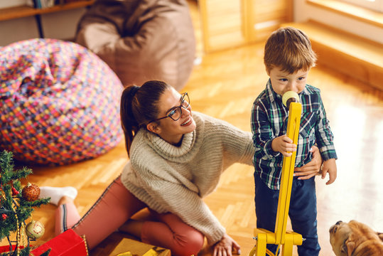 Cute little kid playing with toys while his mom holding him.