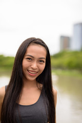 Happy young beautiful Asian woman smiling at the park