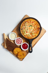 Frittata on a skillet with sauces and bread