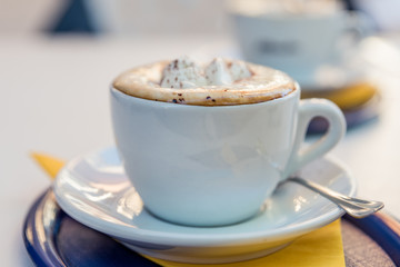 A cup of cappuccino coffee with saucer and spoon