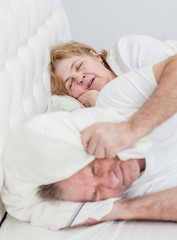 The elderly man covered his ears with a pillow so as not to hear the snoring of his wife. Focesed on woman