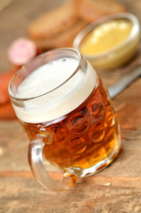 Cold glass of beer, sausage, mustard and bread in the background - vertical photo