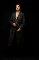 Obraz na płótnie Canvas Girl in coat posing on a black background in the studio. The model is standing upright.