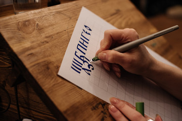 View on big sheet of white paper canvas with word calligraphy spelled on top using brush with black ink by font designer or creative artist freelancer working on project in home studio