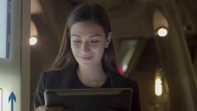 Portrait of smiling young businesswoman working on pc tablet in subway. Caucasian woman using online chat on her digital tablet Wireless   communication concept