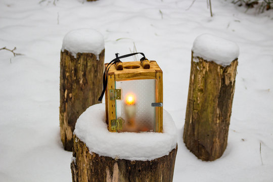 Wooden lantern candlestick in the winter forest

