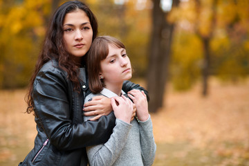 Fototapeta premium Pretty woman and teen girl are posing in autumn park. Beautiful landscape at fall season.
