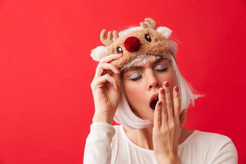 Woman dressed in carnival christmas costume posing isolated over red wall background.